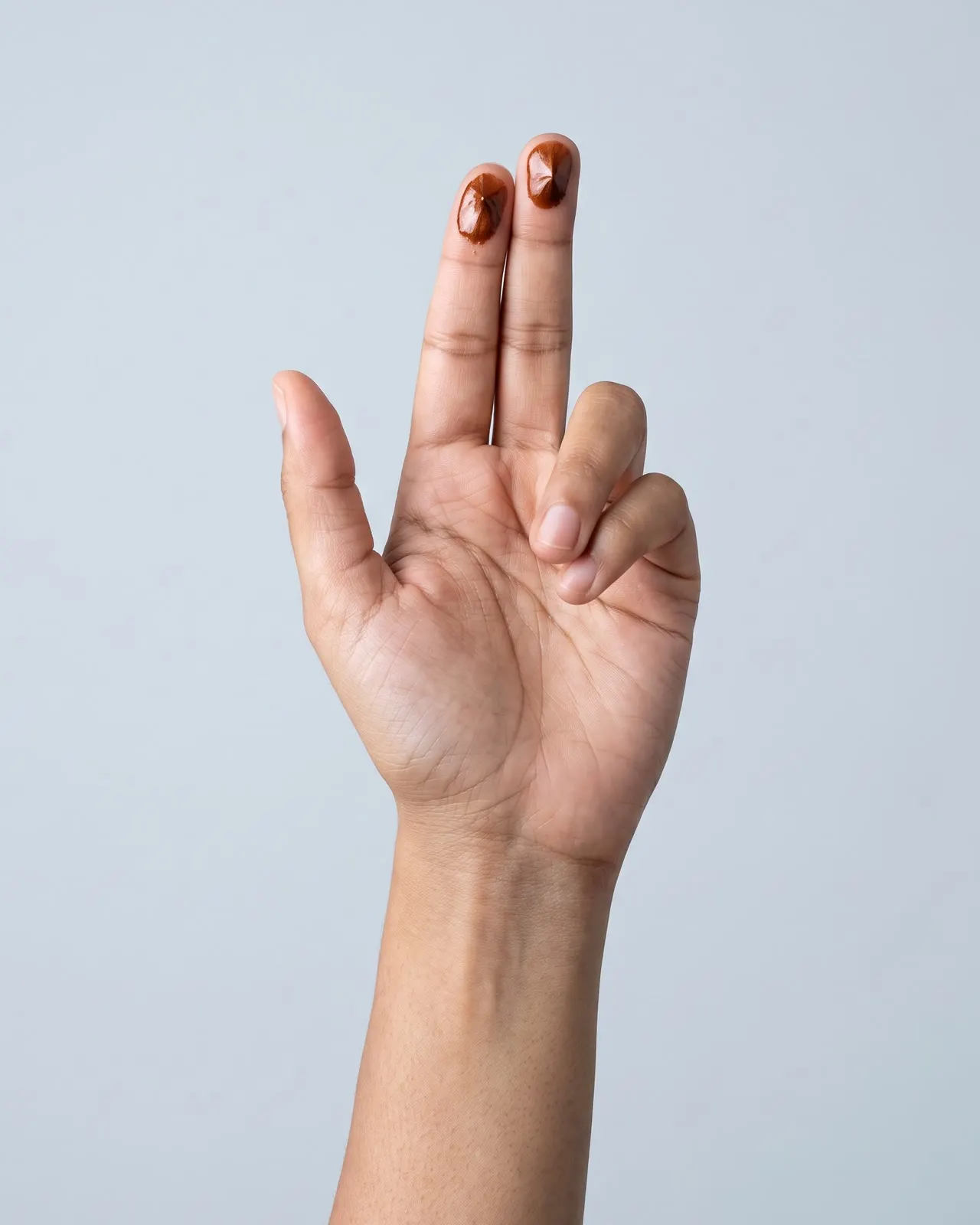 Hand showing two copper hair colour swatches on the fingertips