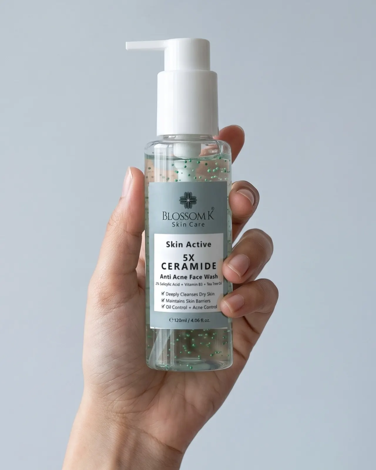 Hand holding BlossomK 5X Ceramide Anti Acne Face Wash with its white pump