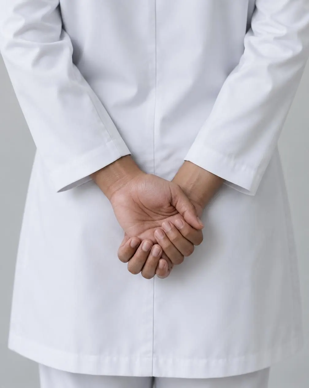 Hands clasped in front of a white salon coat